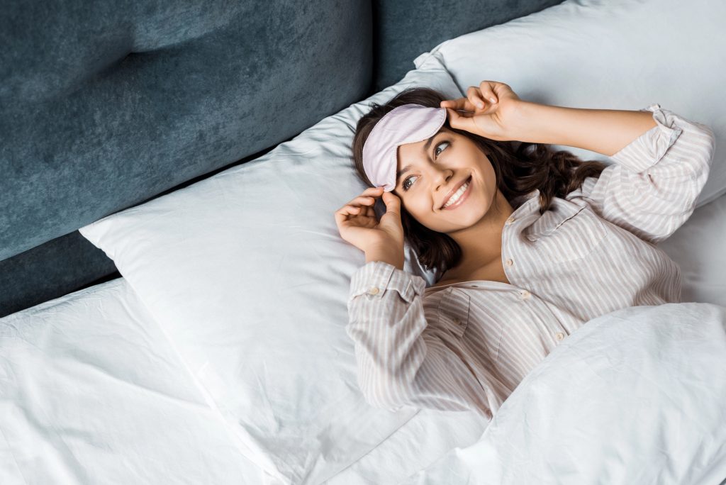 Woman with bright healthy smile in bed. 