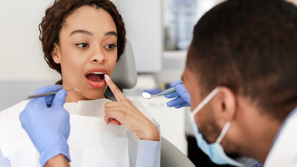 Young woman showing dentist cracked tooth.