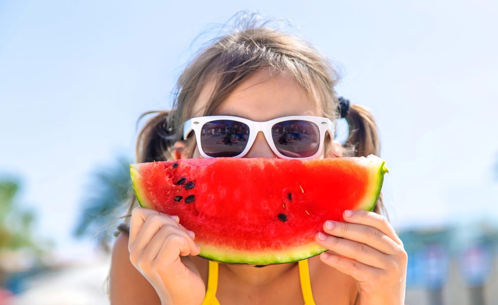 Girl enjoying tooth-healthy watermelon in summer.